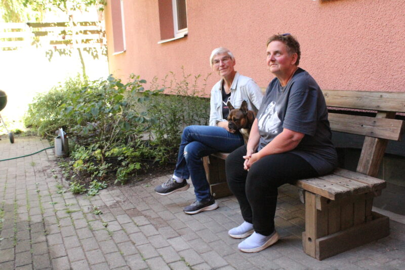 Urszula Striner och Jeanette sitter på en bänk utanför sitt hus i Brf Gillet.