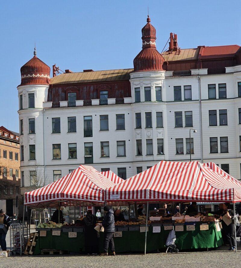 Bilden visar torghandel på Möllevångstorget, med en vacker vi fasad i bakgrunden.